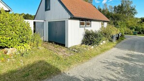 A small, single-story building with a sloped roof, a garage door, and a mailbox. - 2 Person Holiday Home in Garsnas (Gärsnäs)