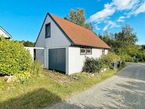 A small, single-story building with a sloped roof, a garage door, and a mailbox. - 2 Person Holiday Home in Garsnas (Gärsnäs)