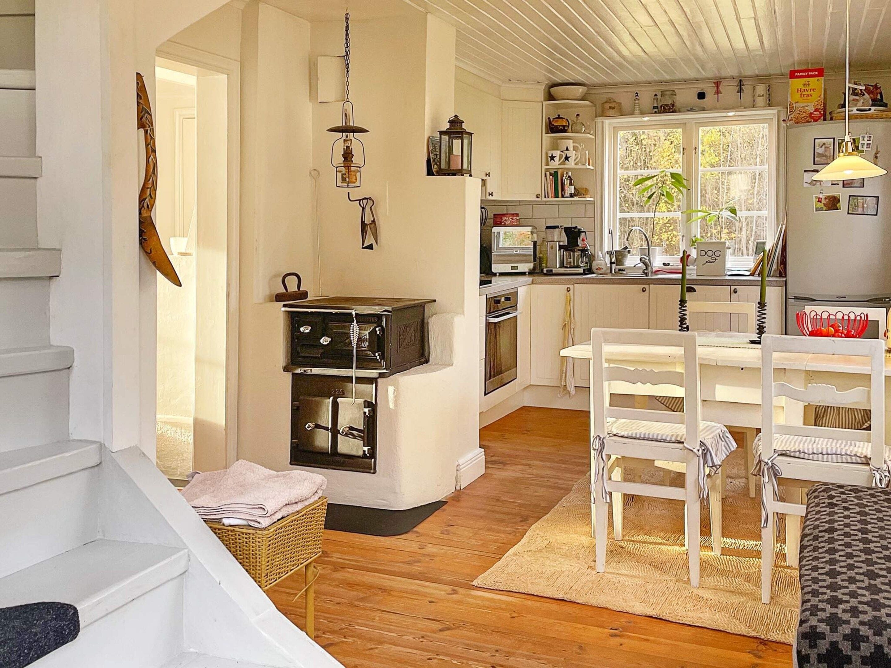 A kitchen with white cabinets, a stove, and a dining area with white chairs.