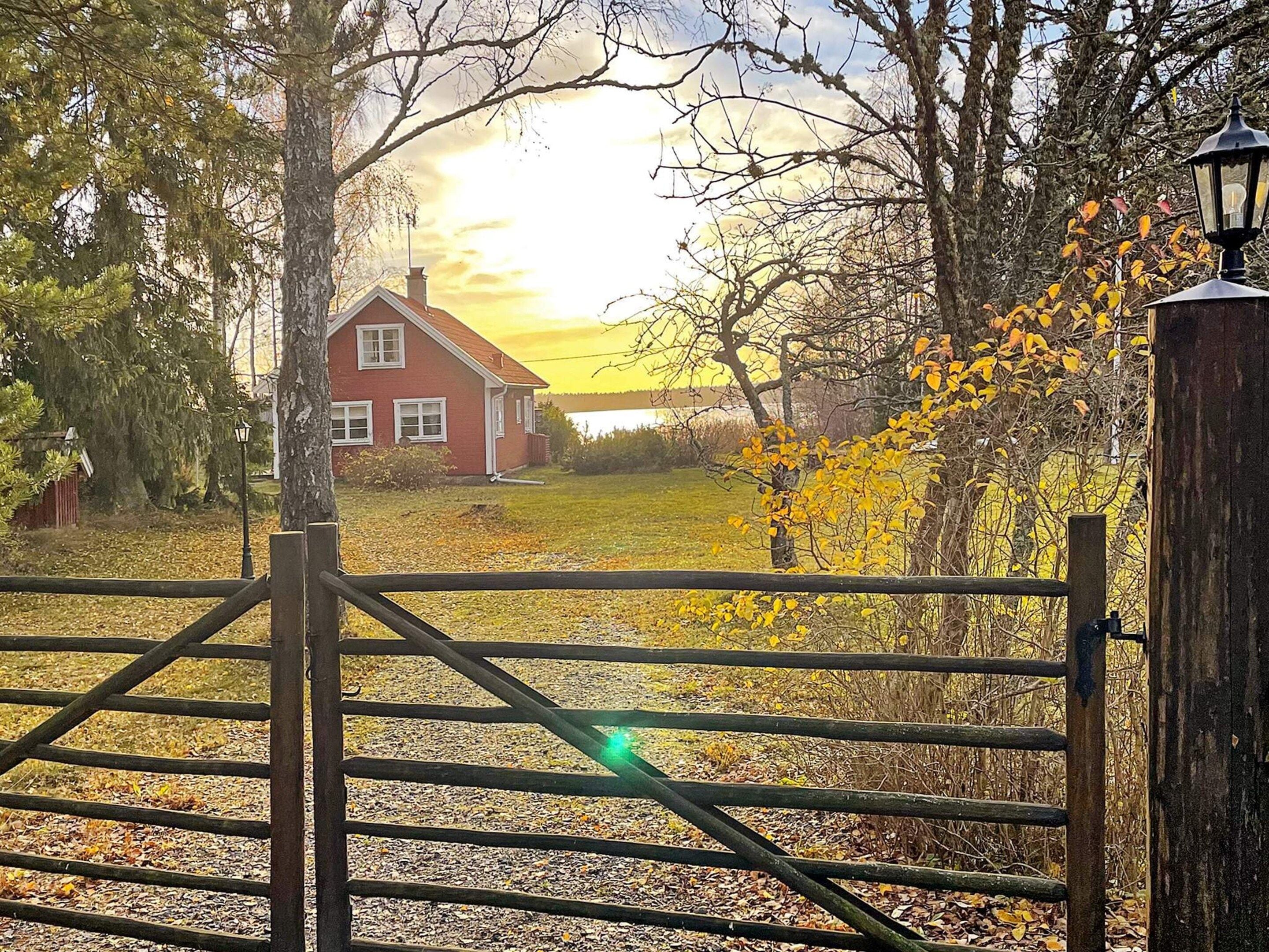 A rural landscape with a red house, a wooden gate, and a lamp post.