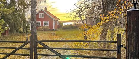 Un paysage rural avec une maison rouge, une porte en bois et un lampadaire.
