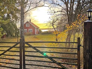 Paisatge rural amb una casa vermella, una porta de fusta i un fanal.