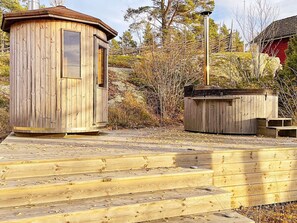 A wooden cabin with a small porch and a metal structure nearby. - 5 Star Holiday Home in Bjorko (Björkö)