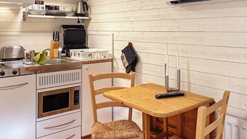 A compact kitchen with a microwave, toaster, and kettle on the countertop.