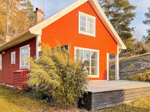 A red wooden house with a white window, a wooden deck, and a small garden. - 5 Star Holiday Home in Bjorko (Björkö)