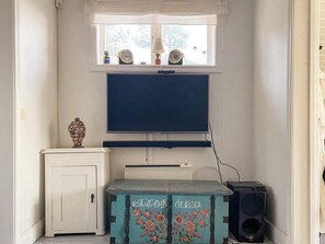 A room with a television mounted on the wall, a cabinet with decorative items, and a speaker. - 5 Star Holiday Home in Bjorko (Björkö)