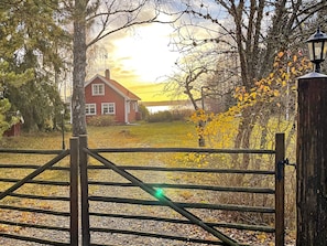 A rural landscape with a red house, a wooden gate, and a lamp post. - 5 Star Holiday Home in Bjorko (Björkö)