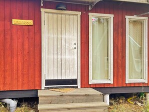 A red wooden building with a beige door and two windows. - 5 Star Holiday Home in Bjorko (Björkö)