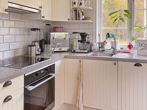 A modern kitchen with a built-in oven, a coffee maker, and a sink. - 5 Star Holiday Home in Bjorko (Björkö)