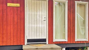 A red wooden building with a beige door and two windows.