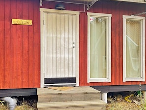 A red wooden building with a beige door and two windows. - 5 Star Holiday Home in Bjorko (Björkö)