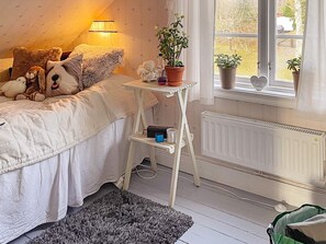 A bedroom with a bed, bedside table, lamp, potted plants, and a radiator. - 5 Star Holiday Home in Bjorko (Björkö)