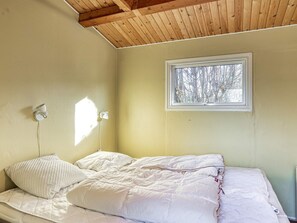 A bedroom with a bed, a window, and a wooden ceiling. - 4 Person Holiday Home in Jaegerspris (Jægerspris)