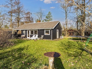 A single-story house with a sloped roof, a front porch with white chairs, and a trampoline in the yard. - 5 Person Holiday Home in Ansager (Ansager)