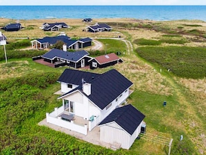 A coastal residential area with multiple houses, some with attached garages, and a clear view of the sea. - 8 Person Holiday Home in Hjorring (Hjørring)