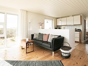A modern living room with a black sofa, wooden flooring, and a view of the outdoors.