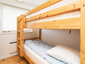 A bunk bed with a wooden frame, a mattress, and a pillow.
