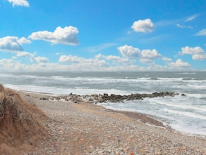 A rocky beach with waves crashing onto the shore and a clear sky. - 8 Person Holiday Home in Hjorring (Hjørring)