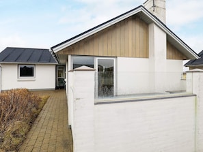 A modern house with a white exterior, a wooden sloped roof, and a visible window.
