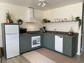 A modern kitchen with a refrigerator, microwave, oven, and dishwasher. There are plants, a coffee maker, and a sink. - 4 Star Holiday Home in Ljungbyhed (Ljungbyhed)