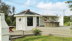A small, white building with a covered porch and a wooden deck. - 6 Person Holiday Home in Meloy (Meloy)