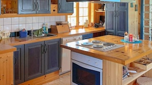 A kitchen with wooden cabinets, a built-in oven, a sink, and a countertop with various items. - 6 Person Holiday Home in Meloy (Meloy)