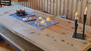 A wooden dining table with candles, a menu, and glasses. - 6 Person Holiday Home in Meloy (Meloy)
