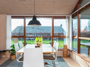 A dining area with a large table, chairs, and a hanging lamp.