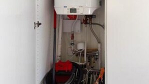 A mechanical room with pipes, a control panel, and a red valve.