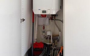 Una sala de máquinas con tuberías, un panel de control y una válvula roja.