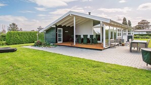 Een modern huis met een overdekte patio, een gazon en een tuin.