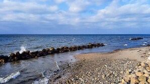 A beach with pebbles, a rocky breakwater, and the sea.