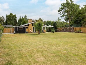 A residential property with a fenced backyard, a wooden deck, and a small building with a chimney.