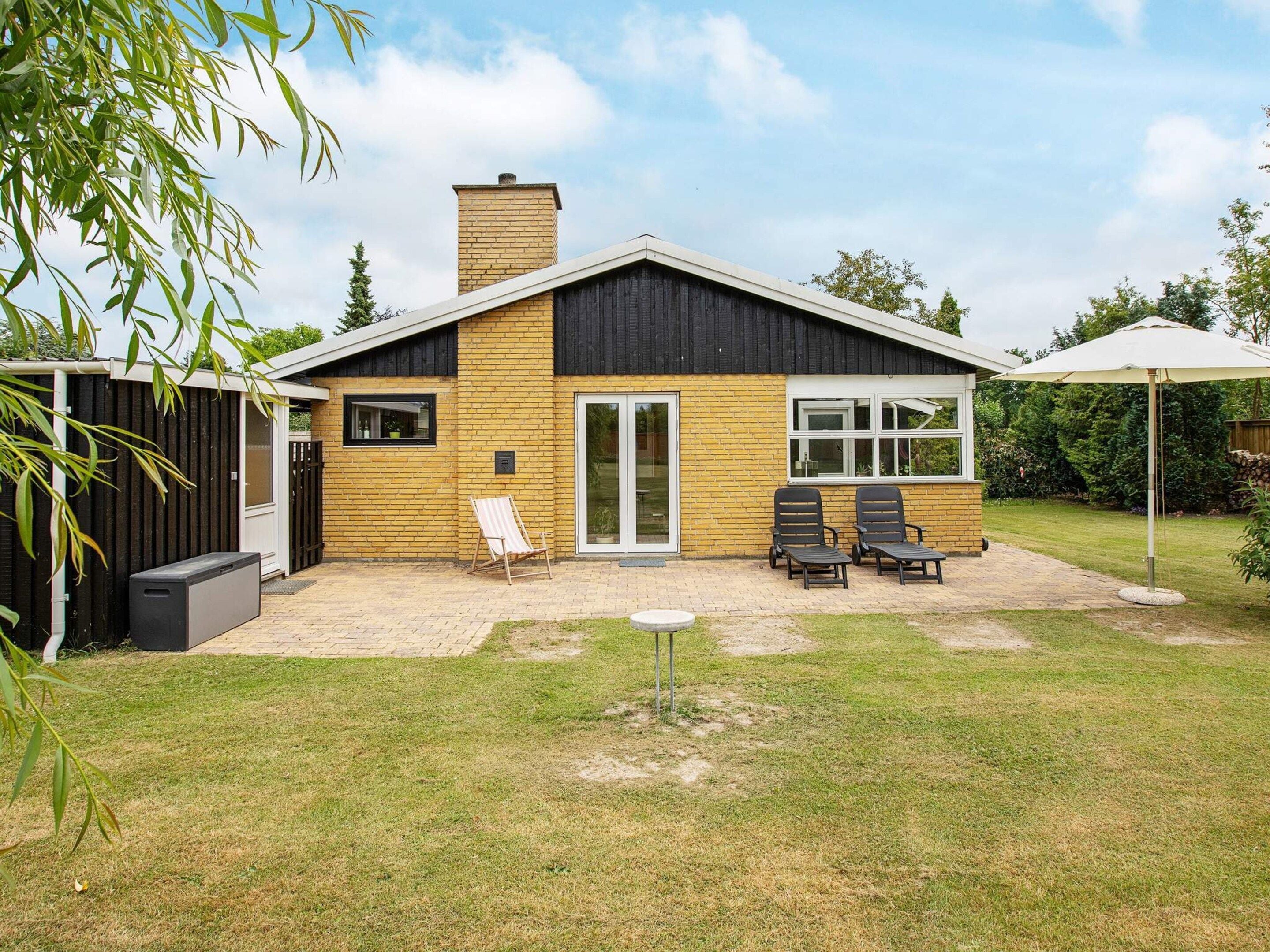 A modern house with a brick exterior, a large sliding glass door, and a patio area with outdoor furniture.