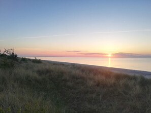 A beach with a sunset over the water. - 5 Person Holiday Home in Vaeggerlose (Vaeggerlose)