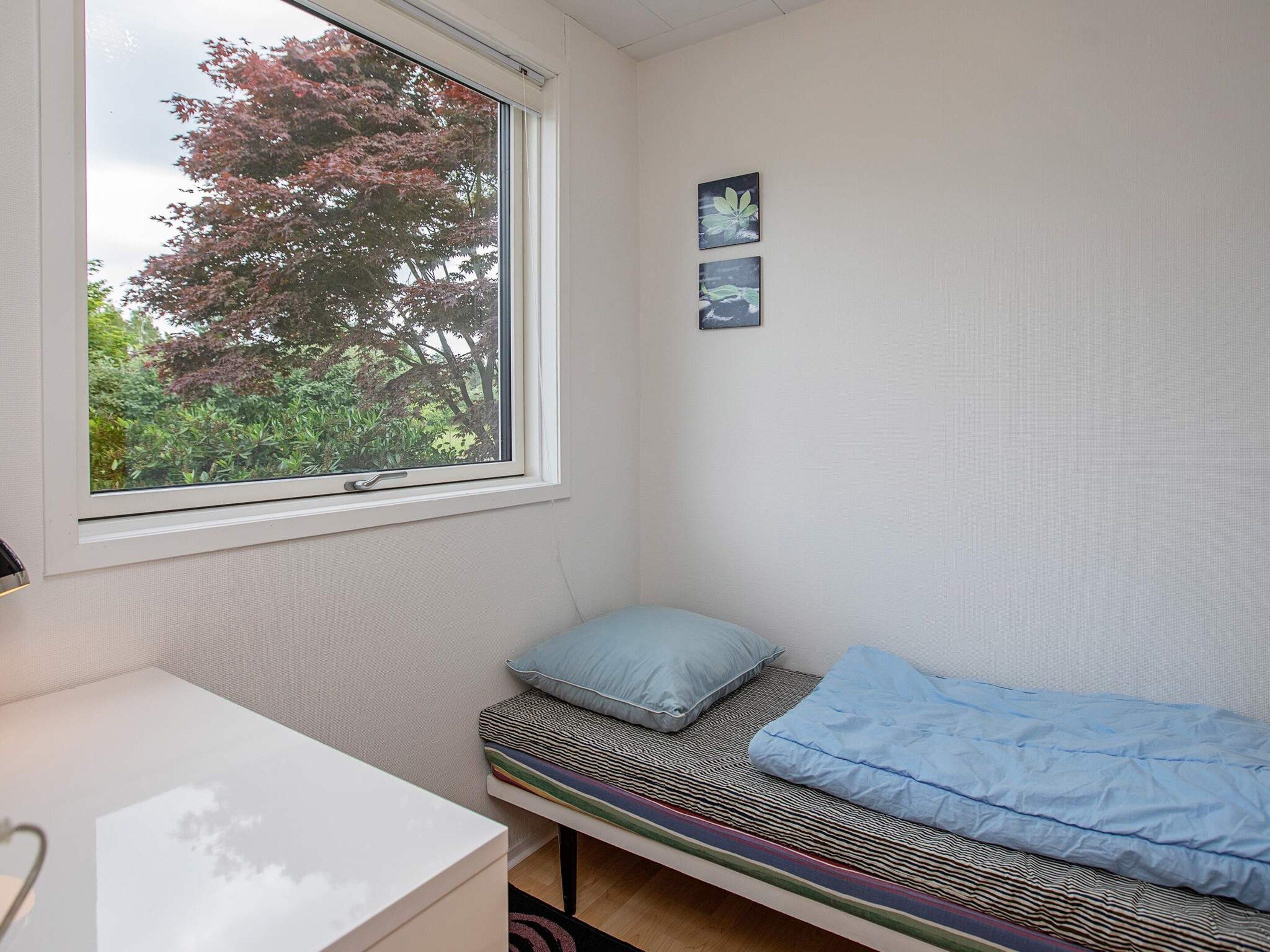 A small room with a single bed, a window, and a desk.