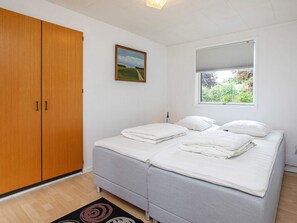 A bedroom with a double bed, a wardrobe, a painting, and a window with a view of greenery. - 5 Person Holiday Home in Vaeggerlose (Vaeggerlose)