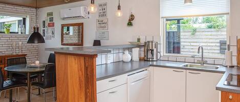 A modern kitchen with a central island, white cabinetry, and a window providing natural light.
