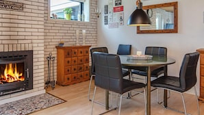 Een gezellig eetgedeelte met een metselaarsschouw, een ronde tafel met stoelen en een wandklok.