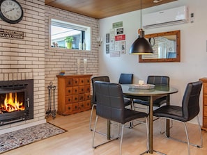 A cozy living room with a fireplace, a dining table with chairs, a clock, and motivational posters on the wall.