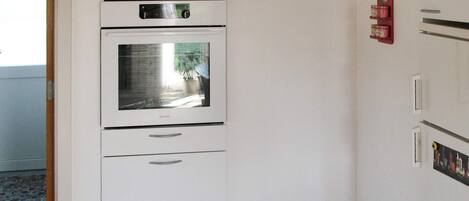 A kitchen with a built-in oven and a refrigerator.