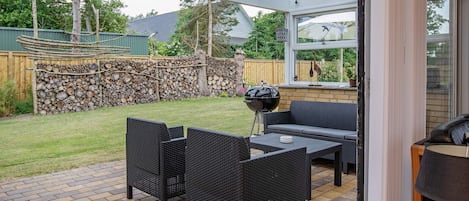 Una terrazza esterna con mobili in vimini, un barbecue e un muro in pietra.
