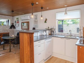 Una cocina moderna con una isla central, armarios blancos y un ventanal que proporciona luz natural.