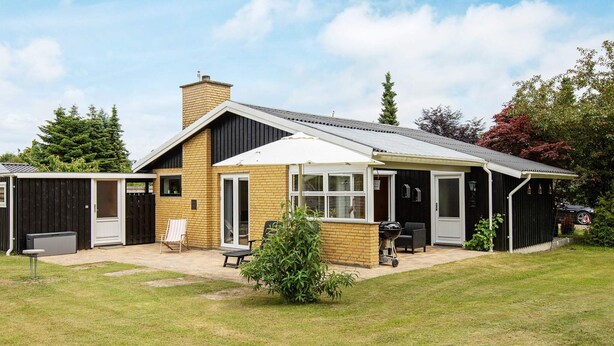 Een huis met een overdekte patio, een garage en een omheinde achtertuin.