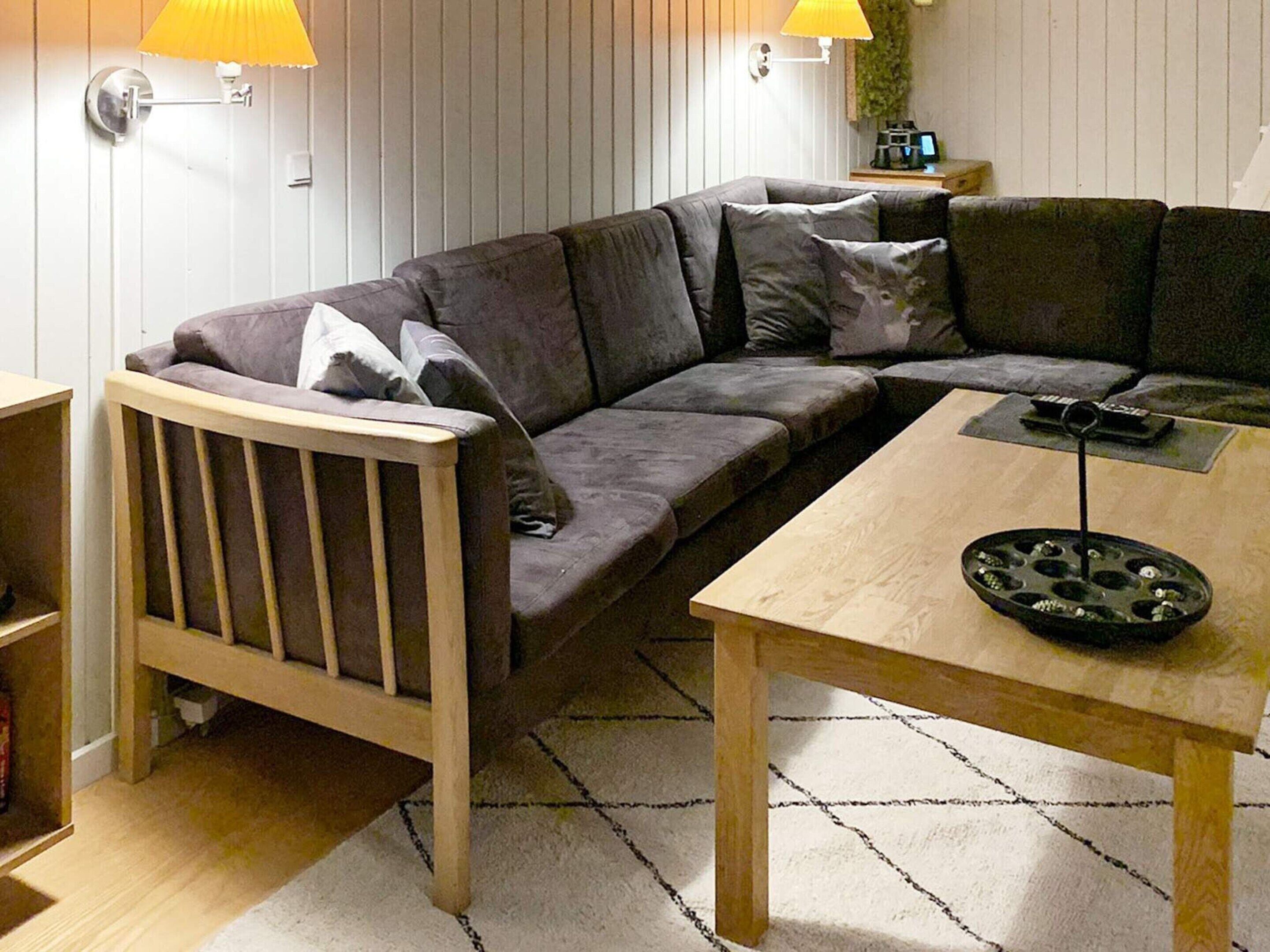 Moderni olohuone, jossa on kulmasohva, puinen sohvapöytä ja pieni sivupöytä.