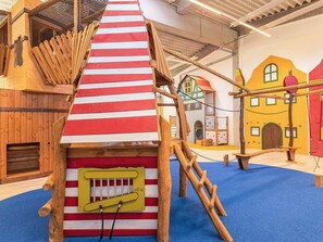 A play area with a climbing structure, a small house, and a wooden playhouse. - 5 Star Holiday Home in Wendtorf (Wendtorf)