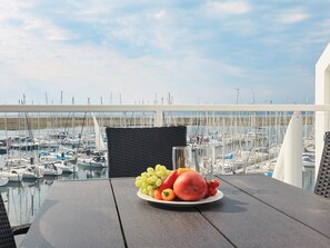 A table with a plate of fruit and a glass of water, overlooking a marina with boats. - 5 Star Holiday Home in Wendtorf (Wendtorf)