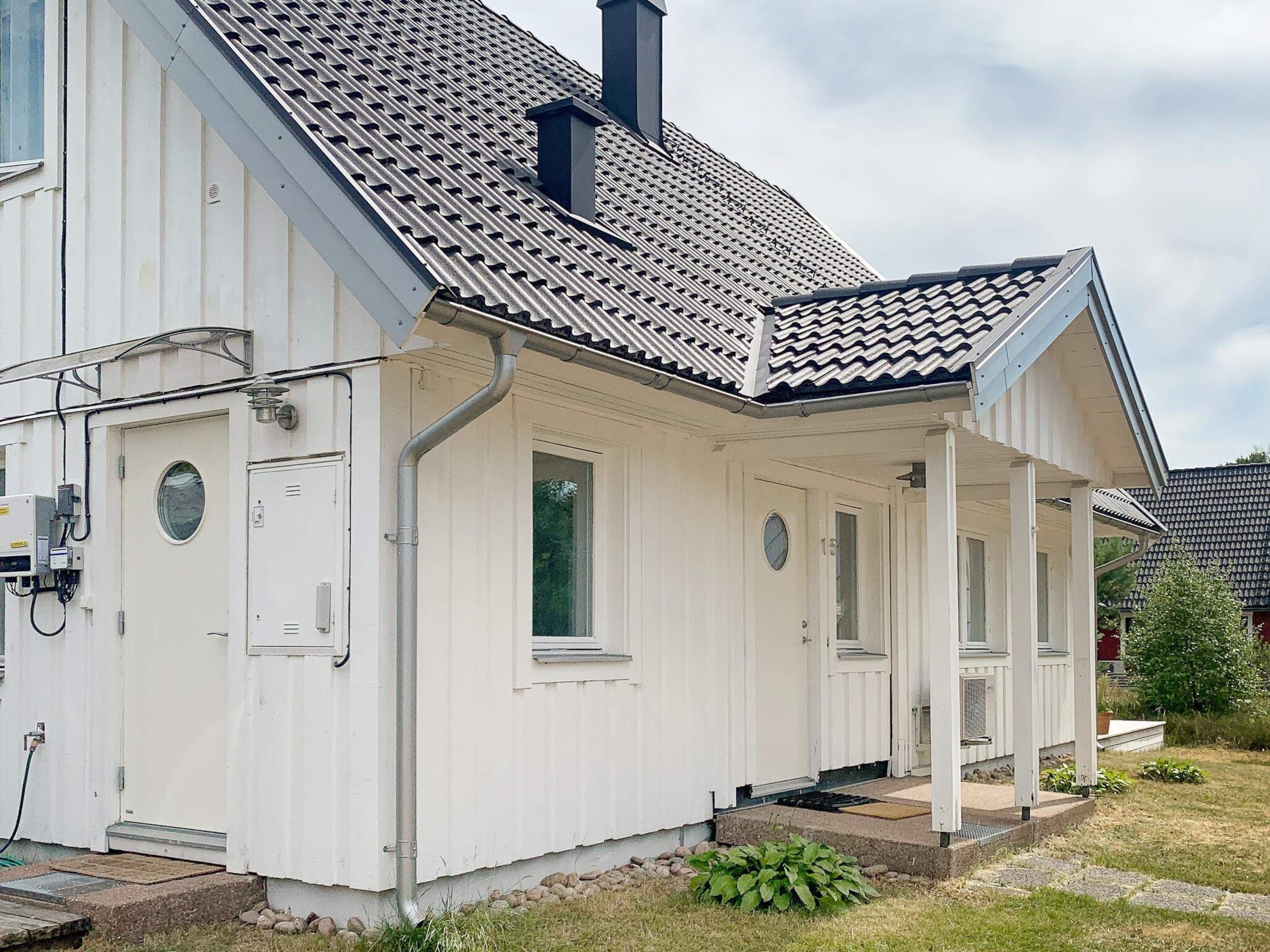 A white building with a tiled roof, a porch, and a chimney.