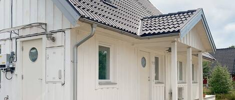 A white building with a tiled roof, a porch, and a chimney.
