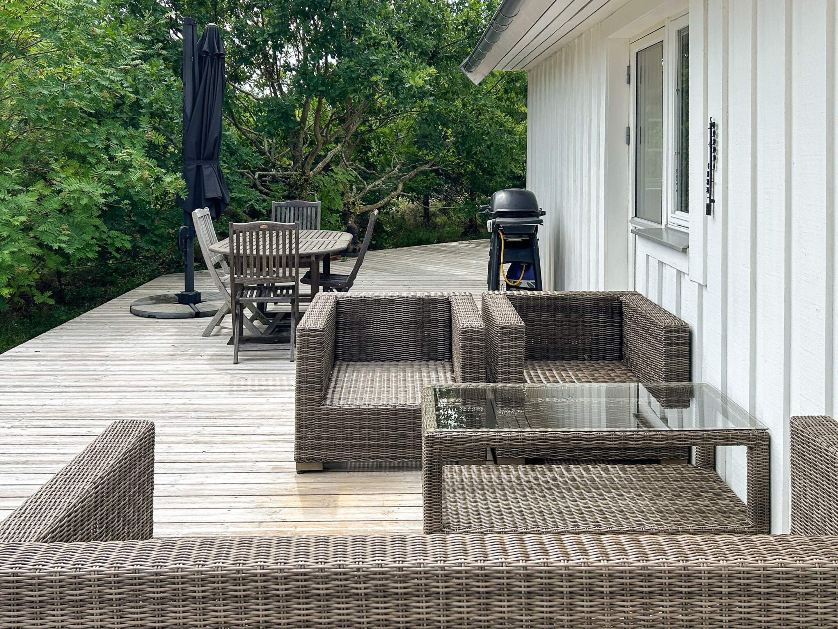 A deck with wicker furniture, including a sofa and chairs, and a table.